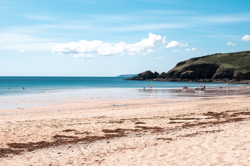A beach with boats and a hill in the background. 