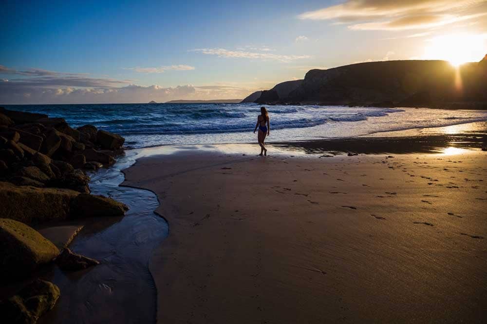 A woman walking along a beach.