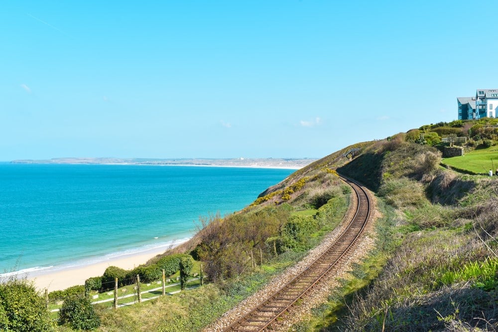 Train tracks on a hill next to a beach.