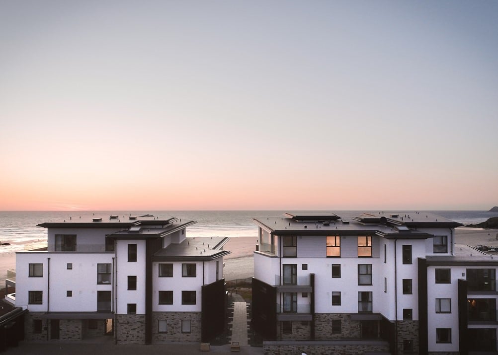 A group of white buildings with a beach in the background.
