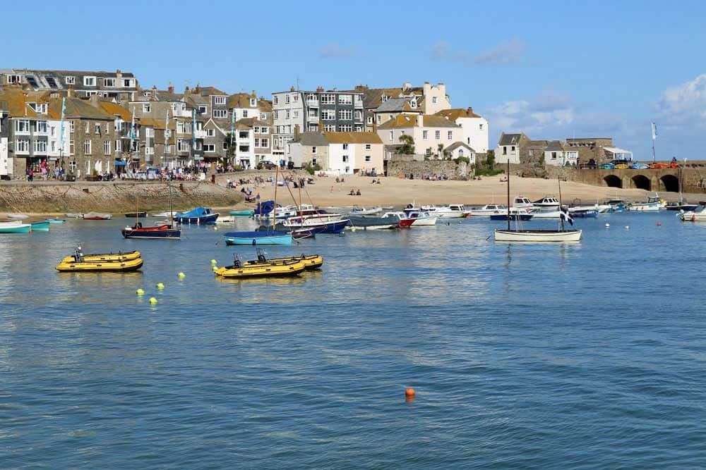 Boats in a harbour overlooked by stone houses.