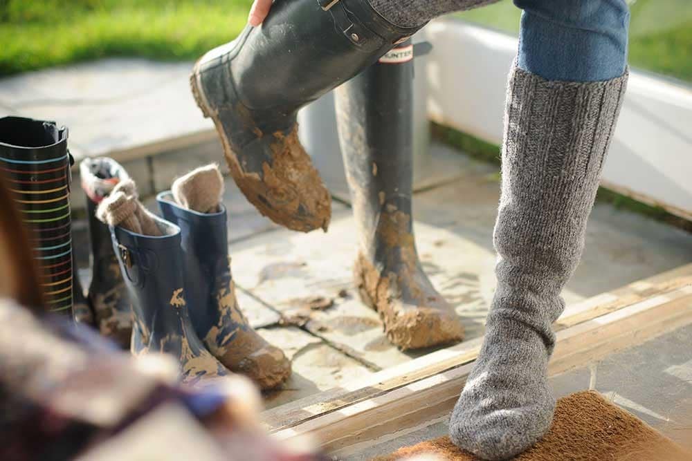 A person pulling off muddy boots. 