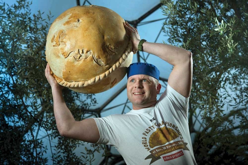A man holding a large round pasty.