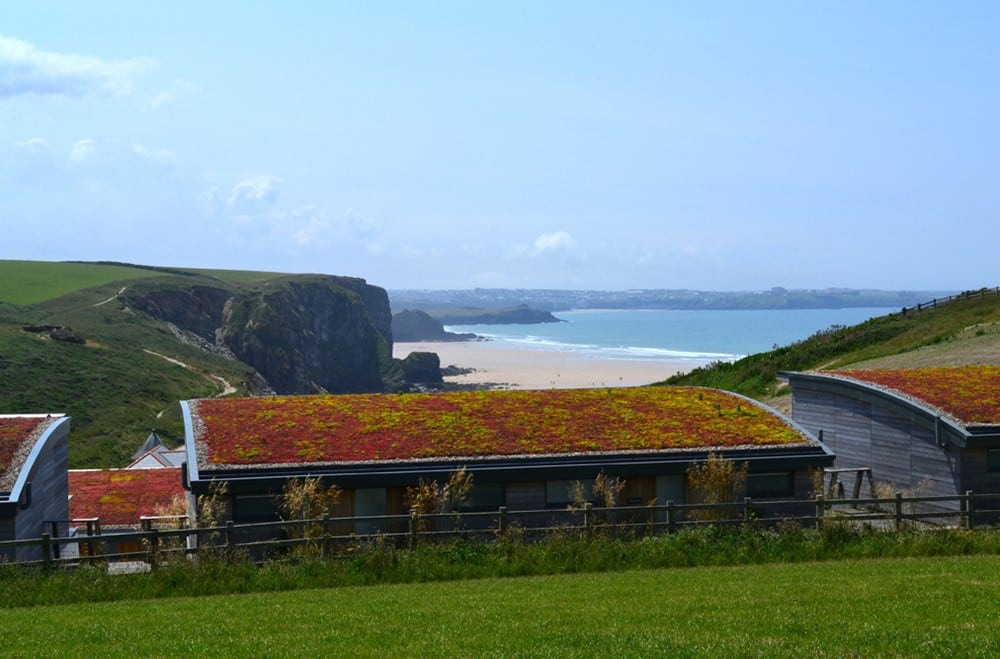 A building with a mossy roof and a beach in the background. 