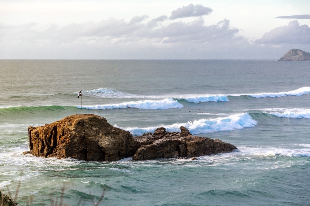 A rock in the ocean with a Cornish flag on it.