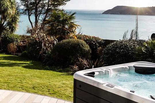 Bubbling hot tub in a garden overlooking the sea.