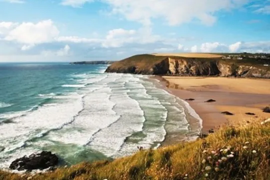 Clifftop view of waves crashing onto a beach.