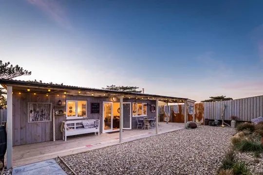Modern wooden property with a pebbled outdoor area at dusk.