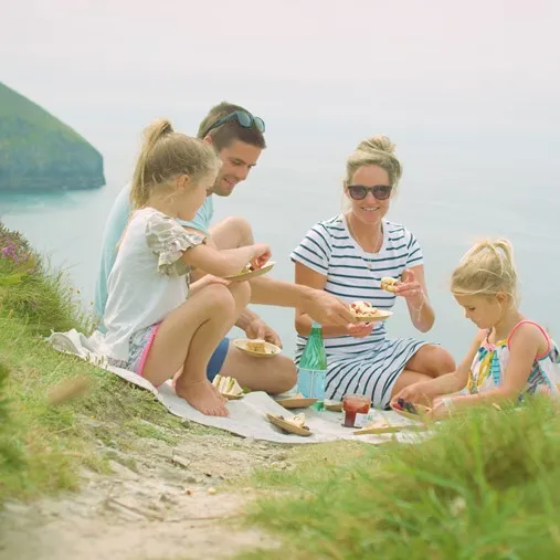 Family having a picnic on a clifftop overlooking the sea.