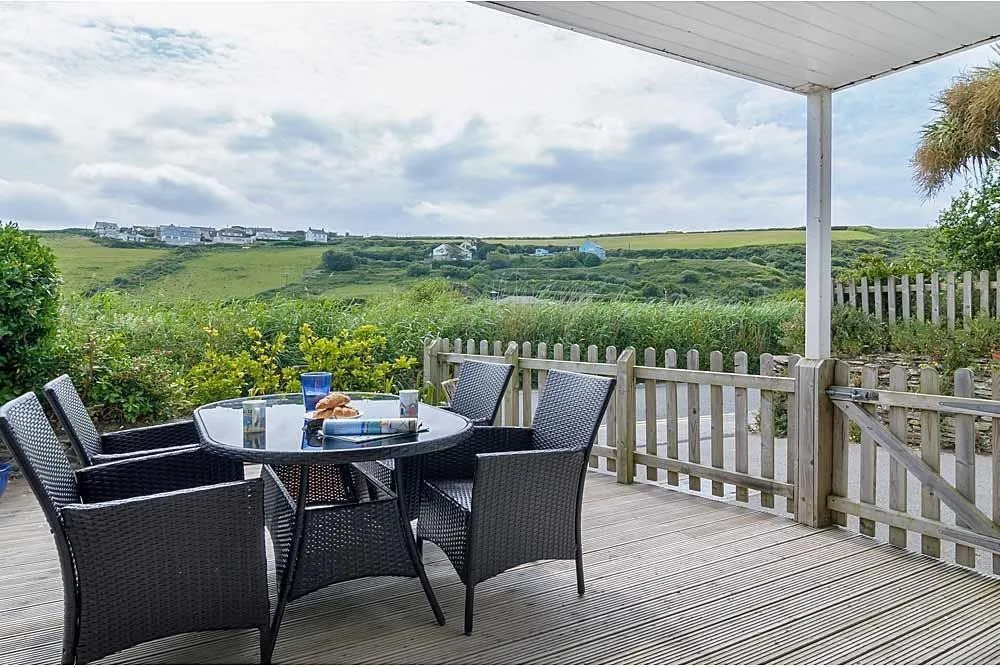 An outdoor wooden seating area overlooking green fields.