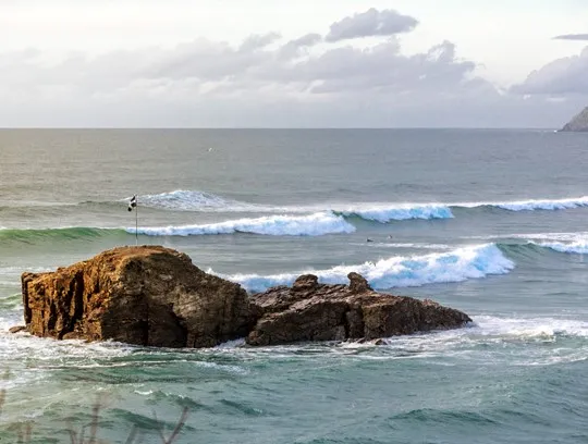 Cornish Flag perched on rocks surrounded by sea.