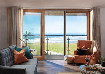 Warm living area with a balcony looking out to sea.