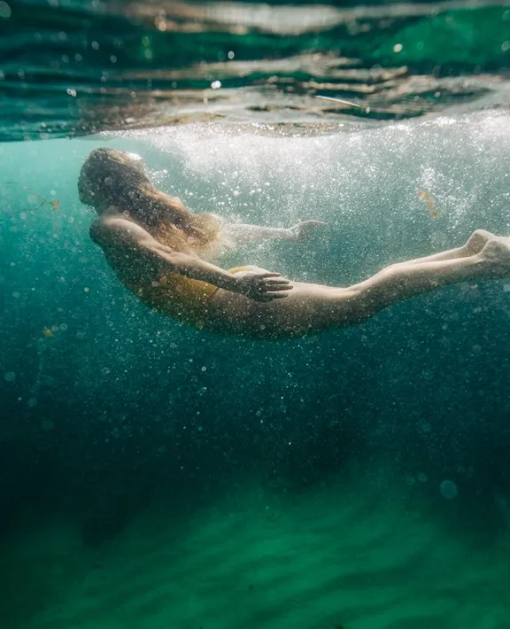 Women in a yellow swimsuit swimming underwater.