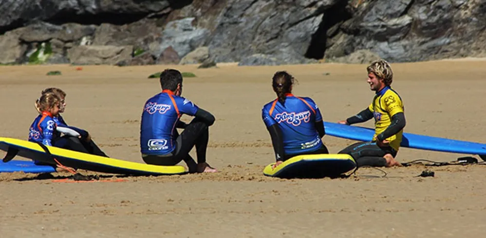 A group of surfers having a lesson on the beach.