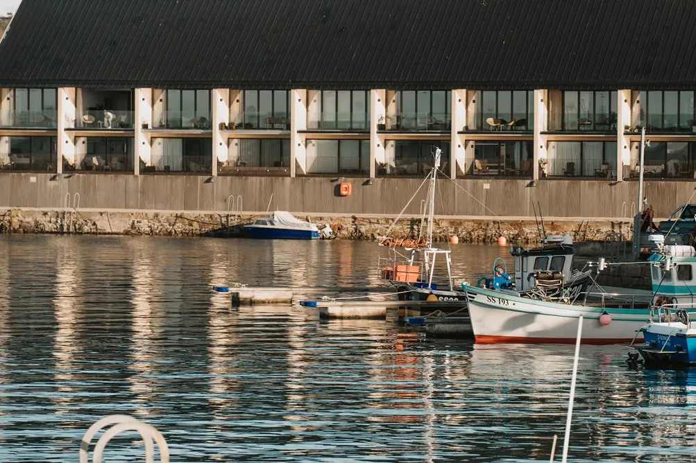 Boats in the water with apartments in the background.