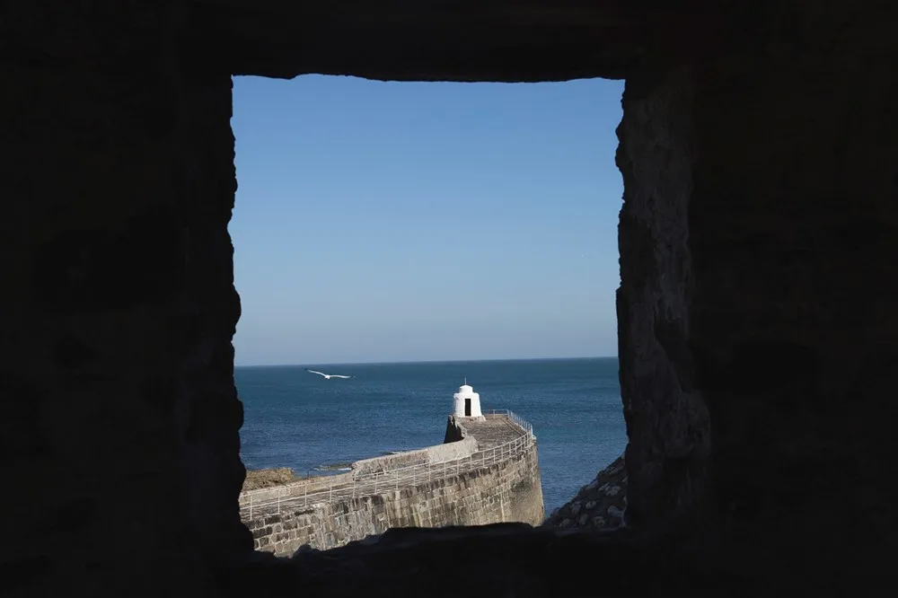 View of a seawall through a rocky window.