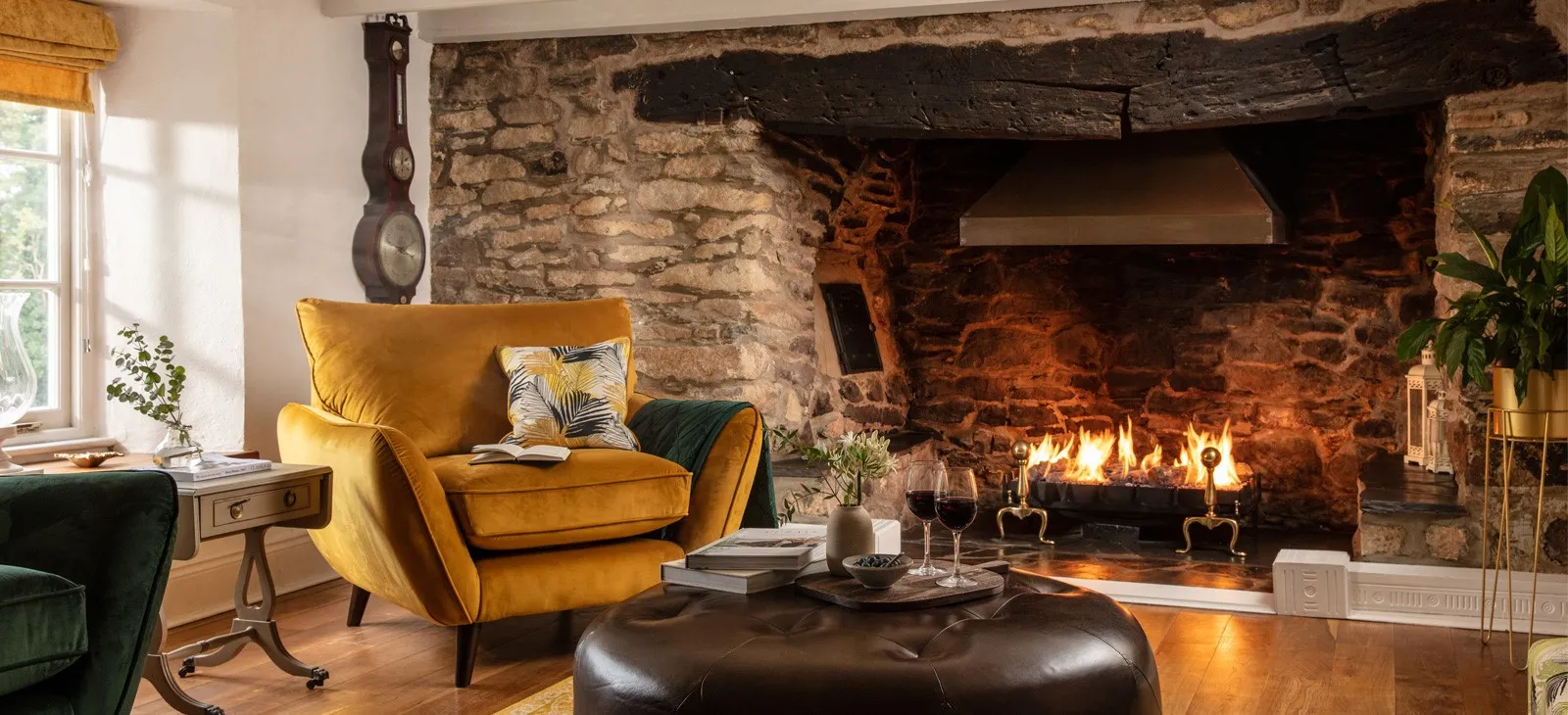 A fireplace with a yellow chair and wine glasses.