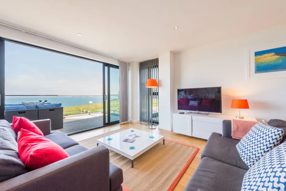 A living room with a glass door and a view of the ocean. 