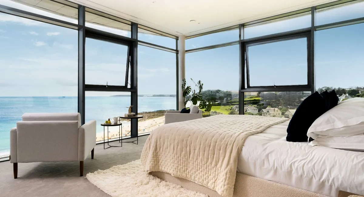 A bedroom with large windows and a large bed.