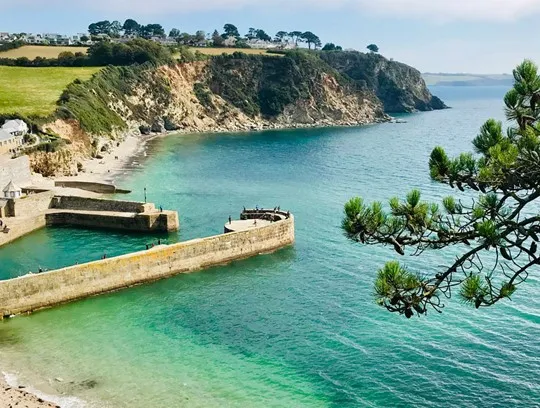 Small beach and harbour with a stone wall.