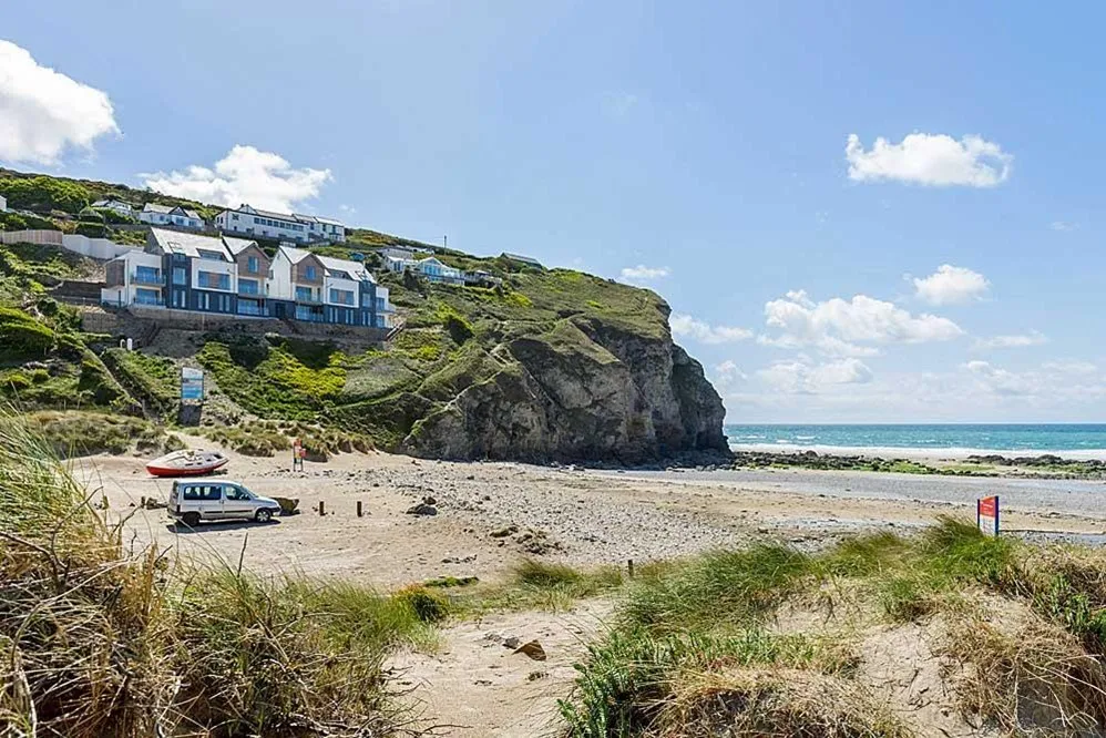 A beach with houses and a car on the side. 