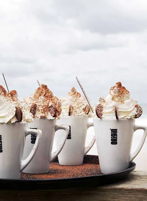 White mugs with whipped cream on top.
