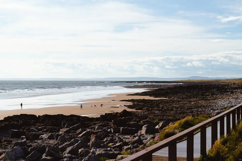 A beach with rocks and a person walking.