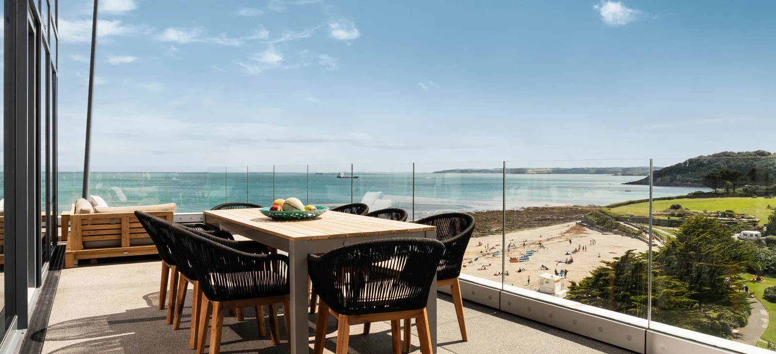 A table and chairs on a balcony overlooking the ocean.