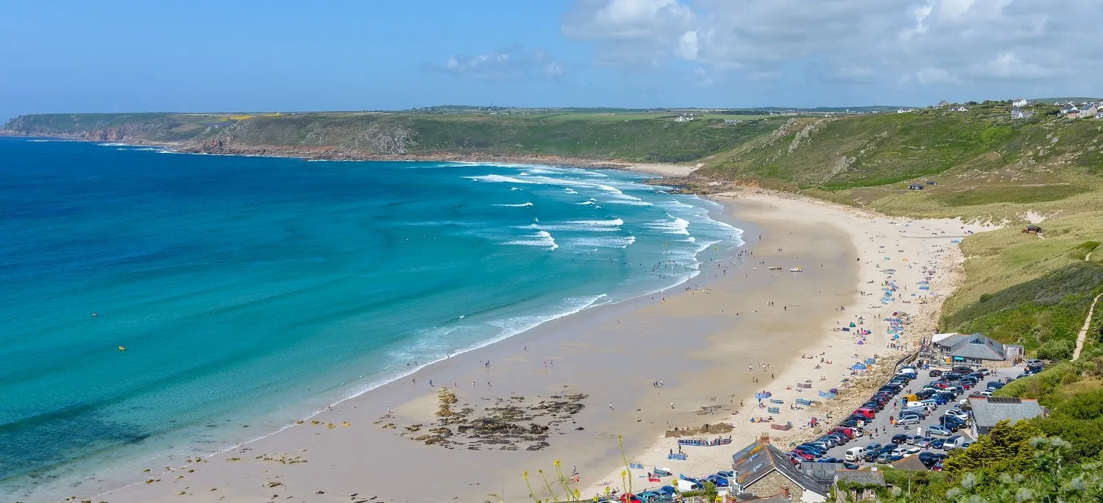 A beach with white sand and swimmers.