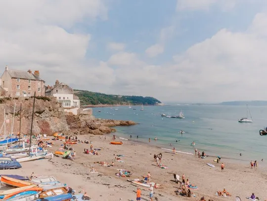 A beach with people and boats on the water.