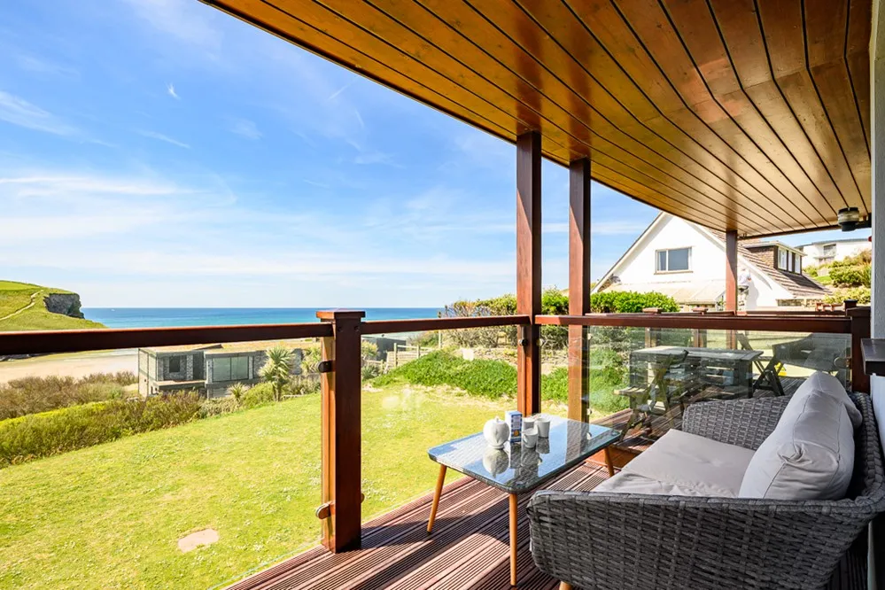 A deck with a table and chairs overlooking the ocean. 