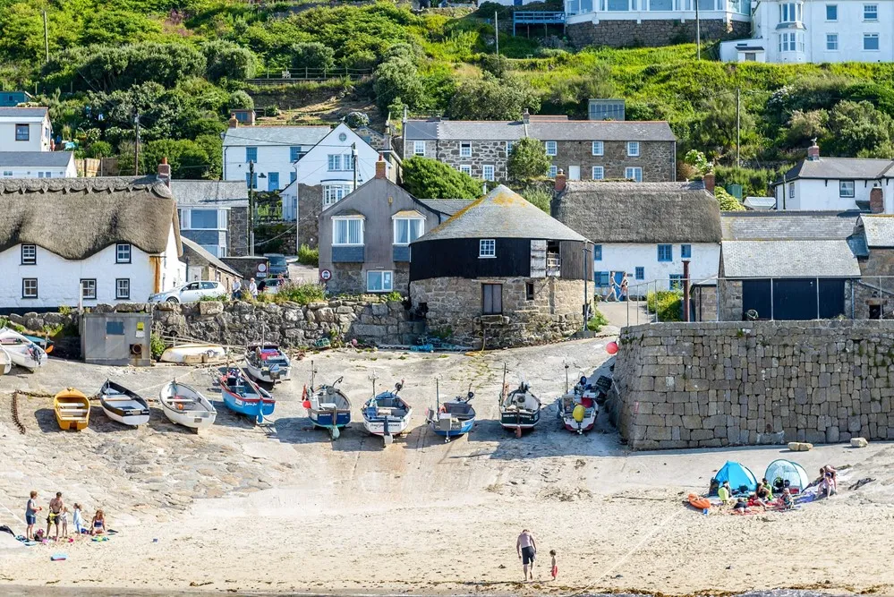 Boats on a beach overlooked by cottages.