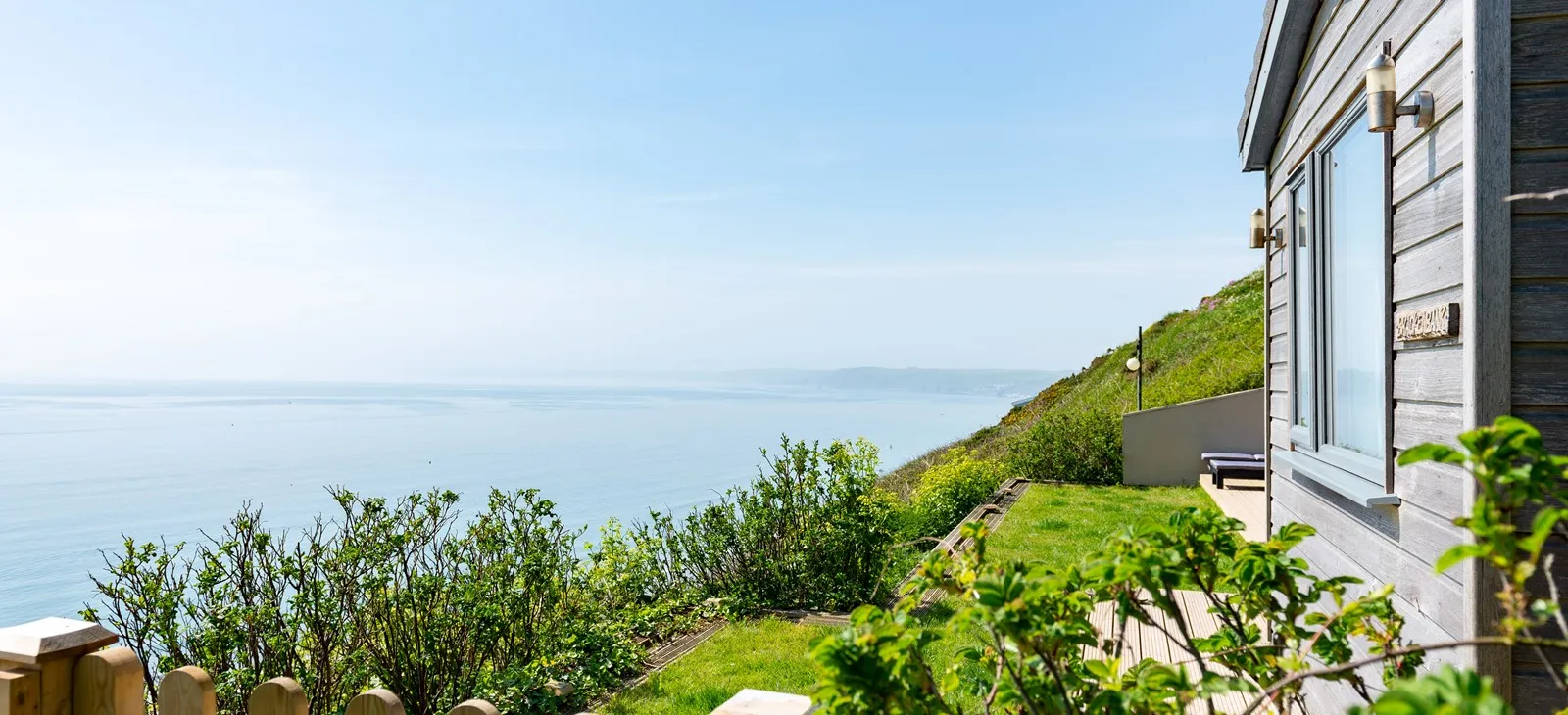 A grassy hill with the sea in the background.