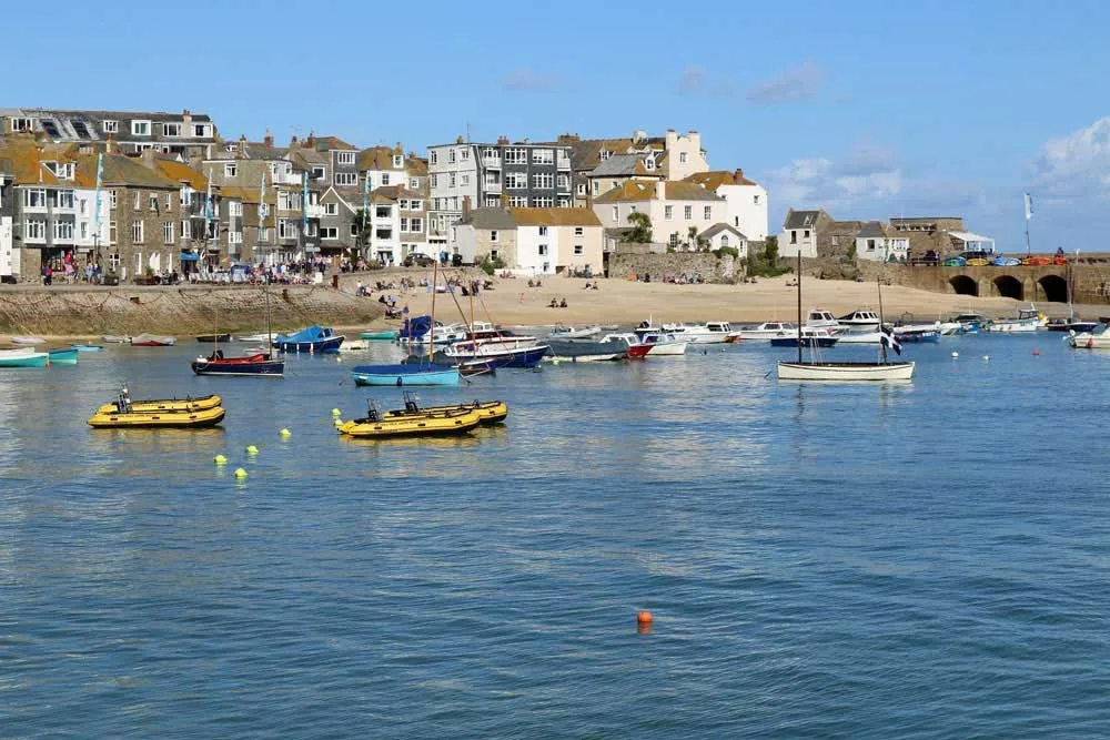 Boats in a harbour overlooked by stone houses.