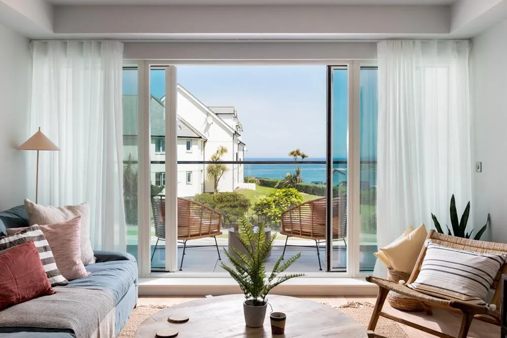 A living room with a couch and chairs and a table with a plant. 