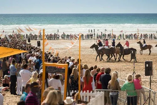 A group of people on horses on a beach. 