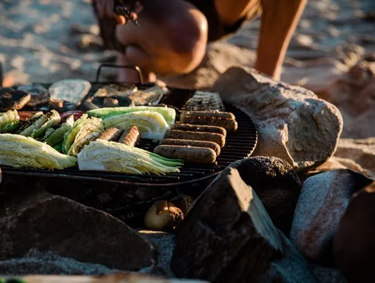 Food on a grill on a beach.