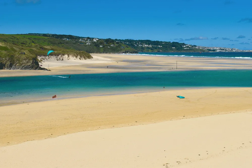 A beach with a person flying a kite.