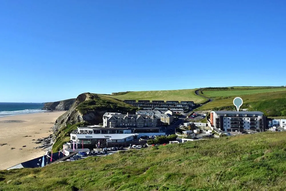 A green hill with buildings and cars parked on it. 