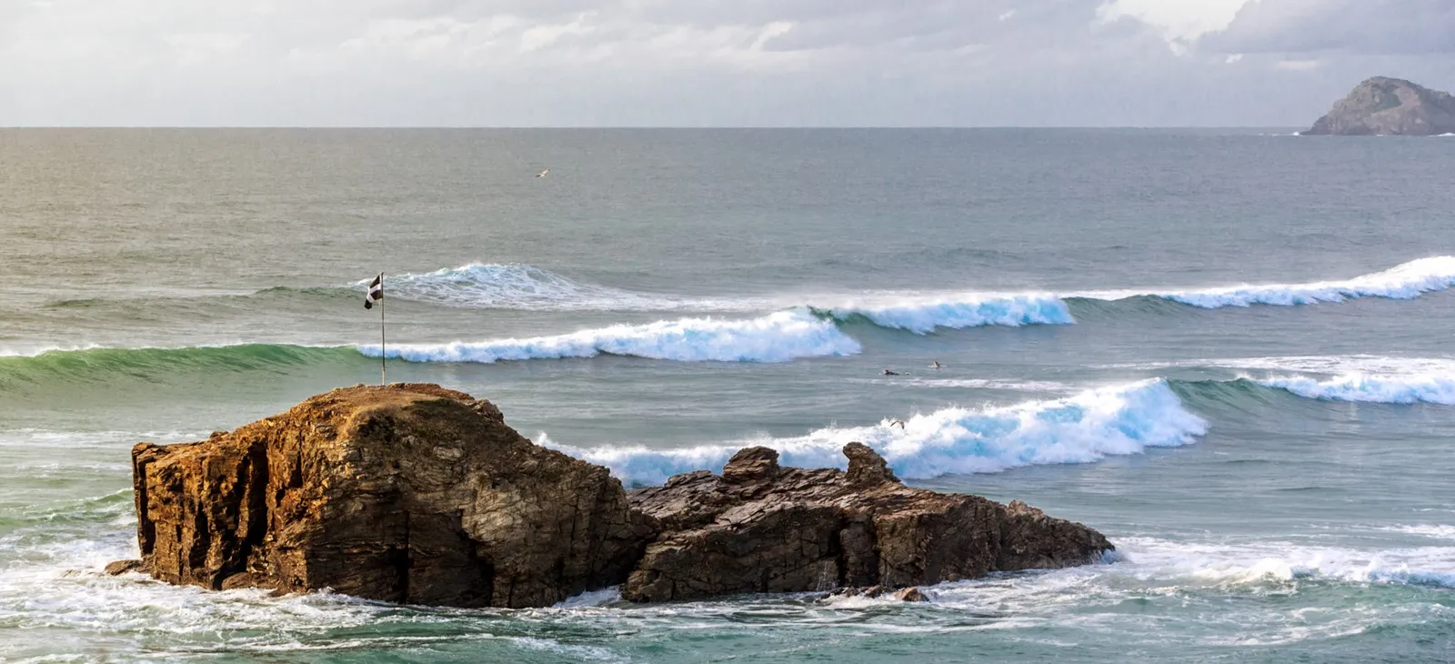 Cornish flag flying on beach rocks.