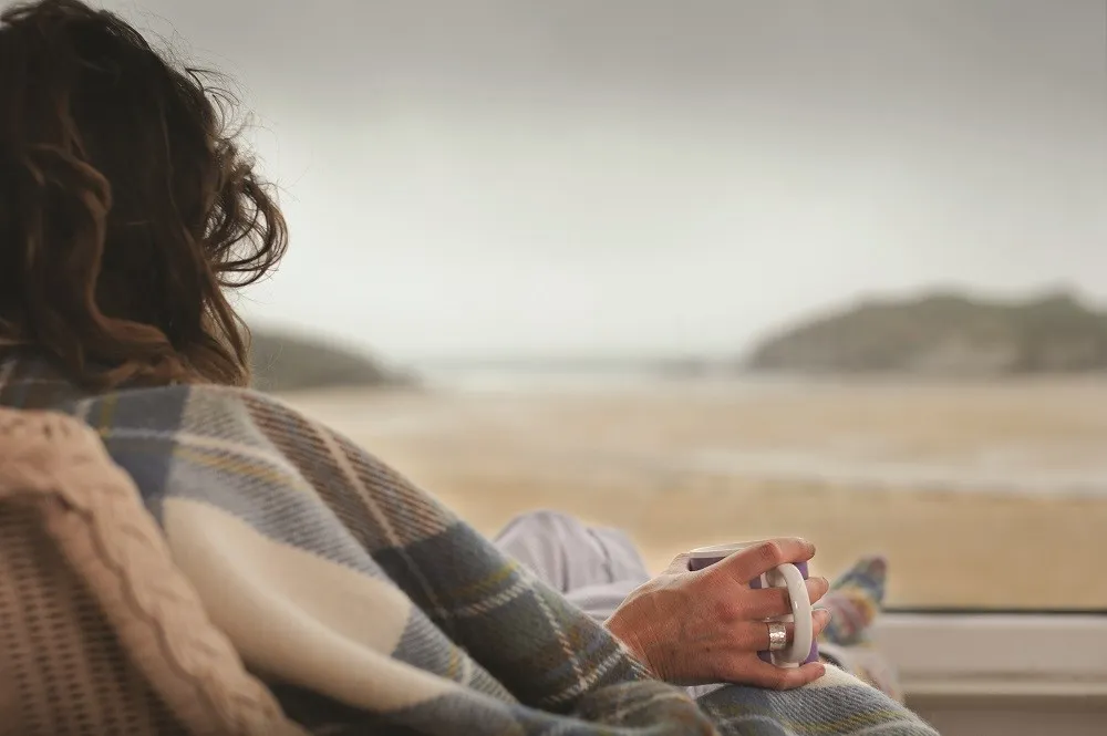 A person holding a cup on the beach.