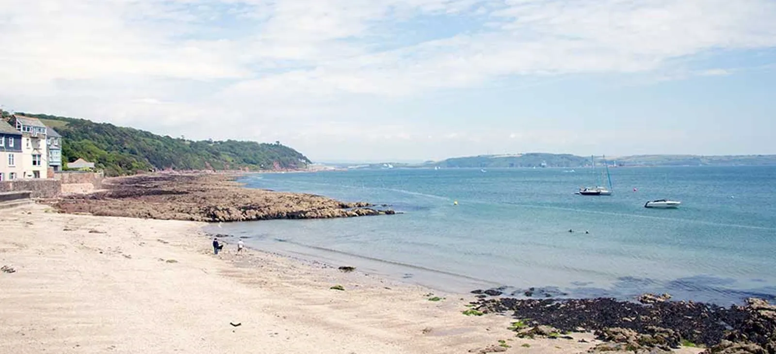 People walking on a rocky beach.