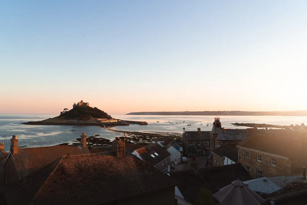 Buildings overlooking the sea and a small island in the distance. 