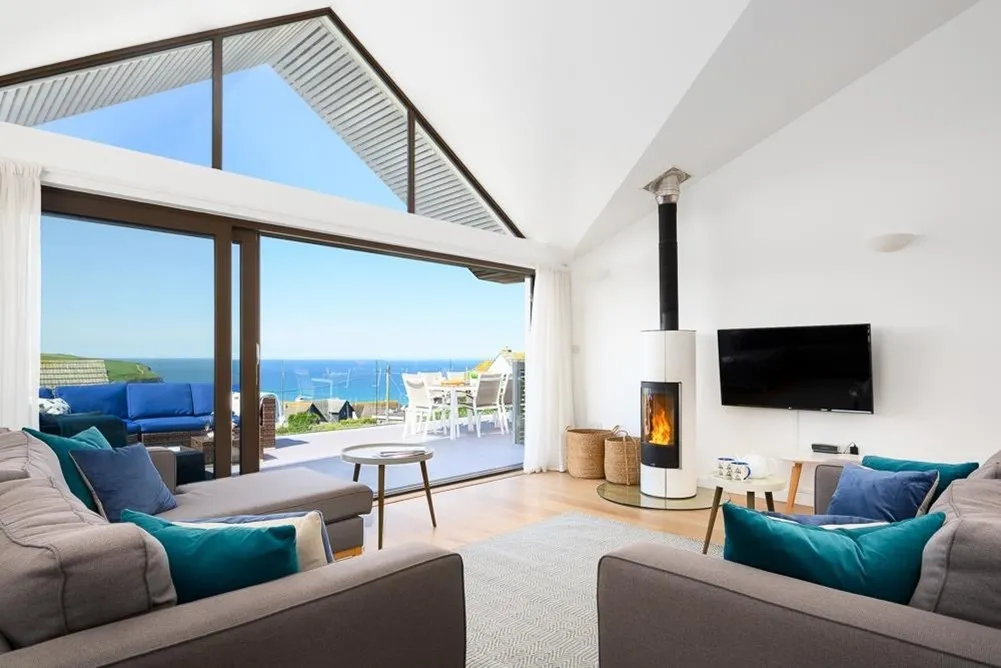 A living room with a fireplace and a view of the ocean. 