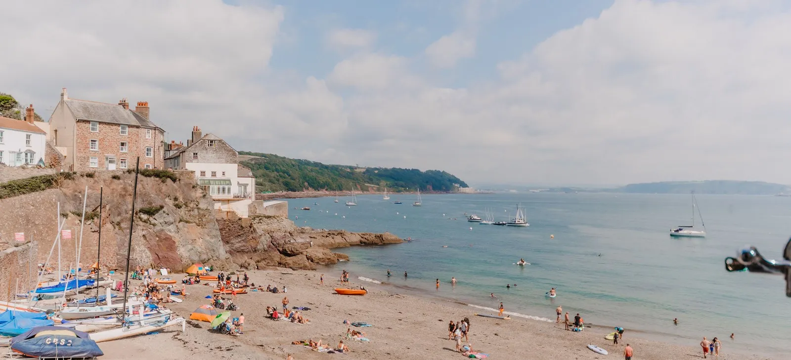 Beach with people and boats in the water.