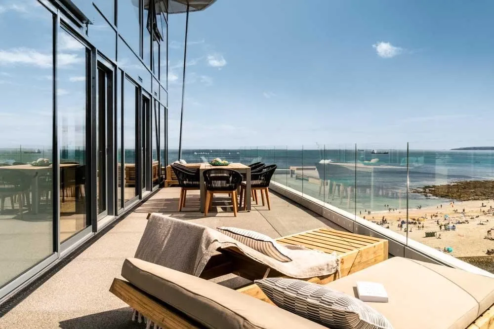 A balcony with chairs and a table on a sunny day.