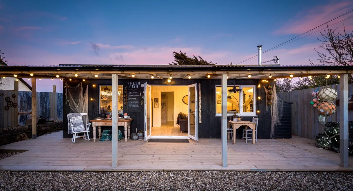A black wooden house with lights on the side.