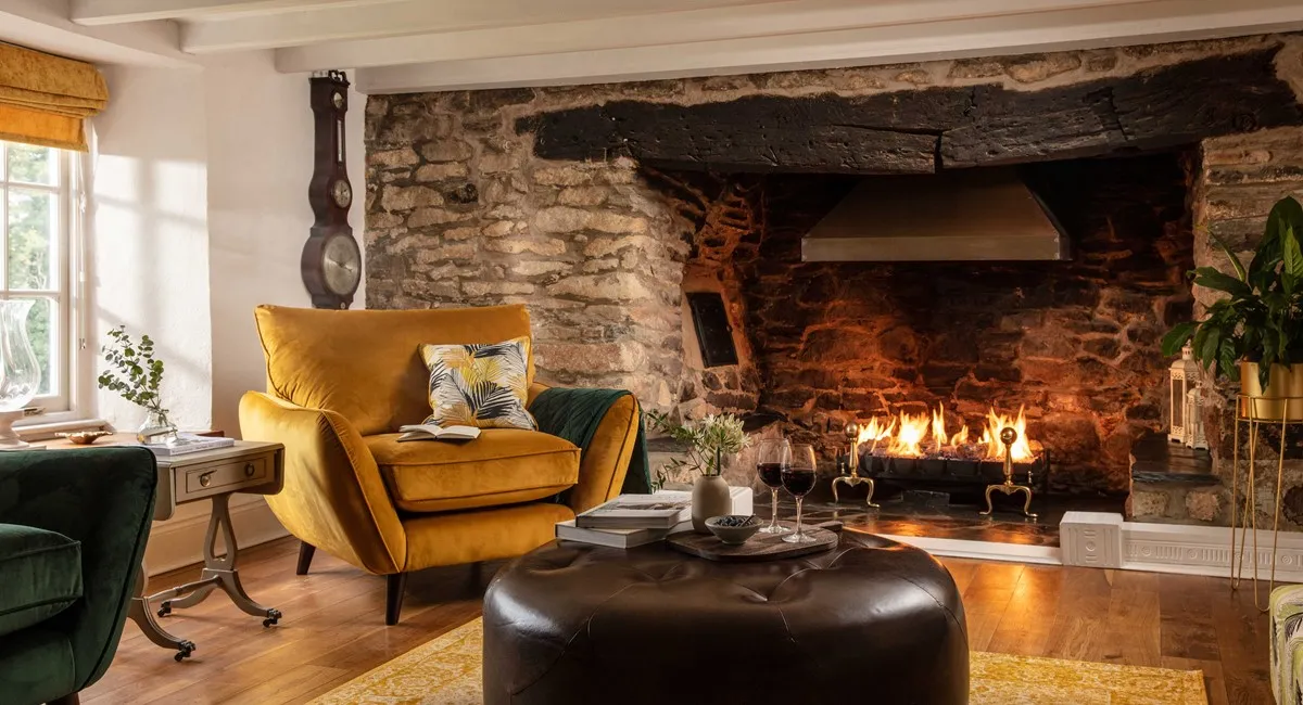 A fireplace with a yellow chair and wine glasses.