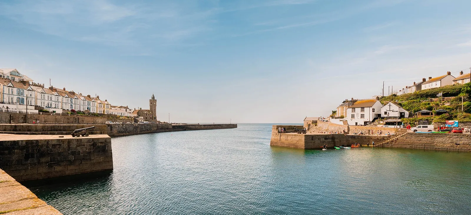 A harbour overlooked by buildings and a tower.