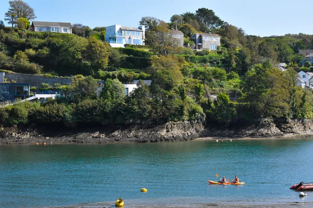 Houses overlooking the sea with people kayaking below.